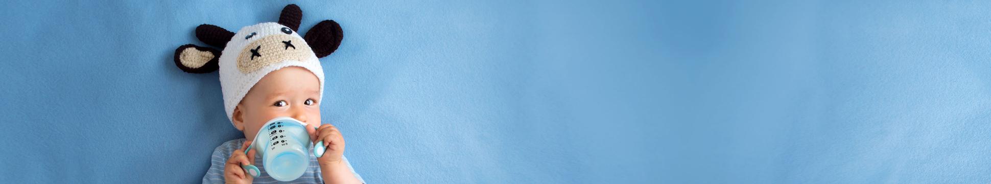 photo of a baby boy wearing a cow cap and drinking milk