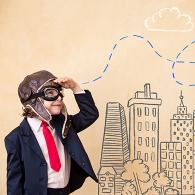 photo of a child looking at a paper plane in front of a town drawing