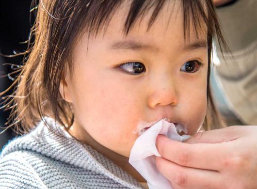 photo of a mom's hand wiping the mouth of her little girl